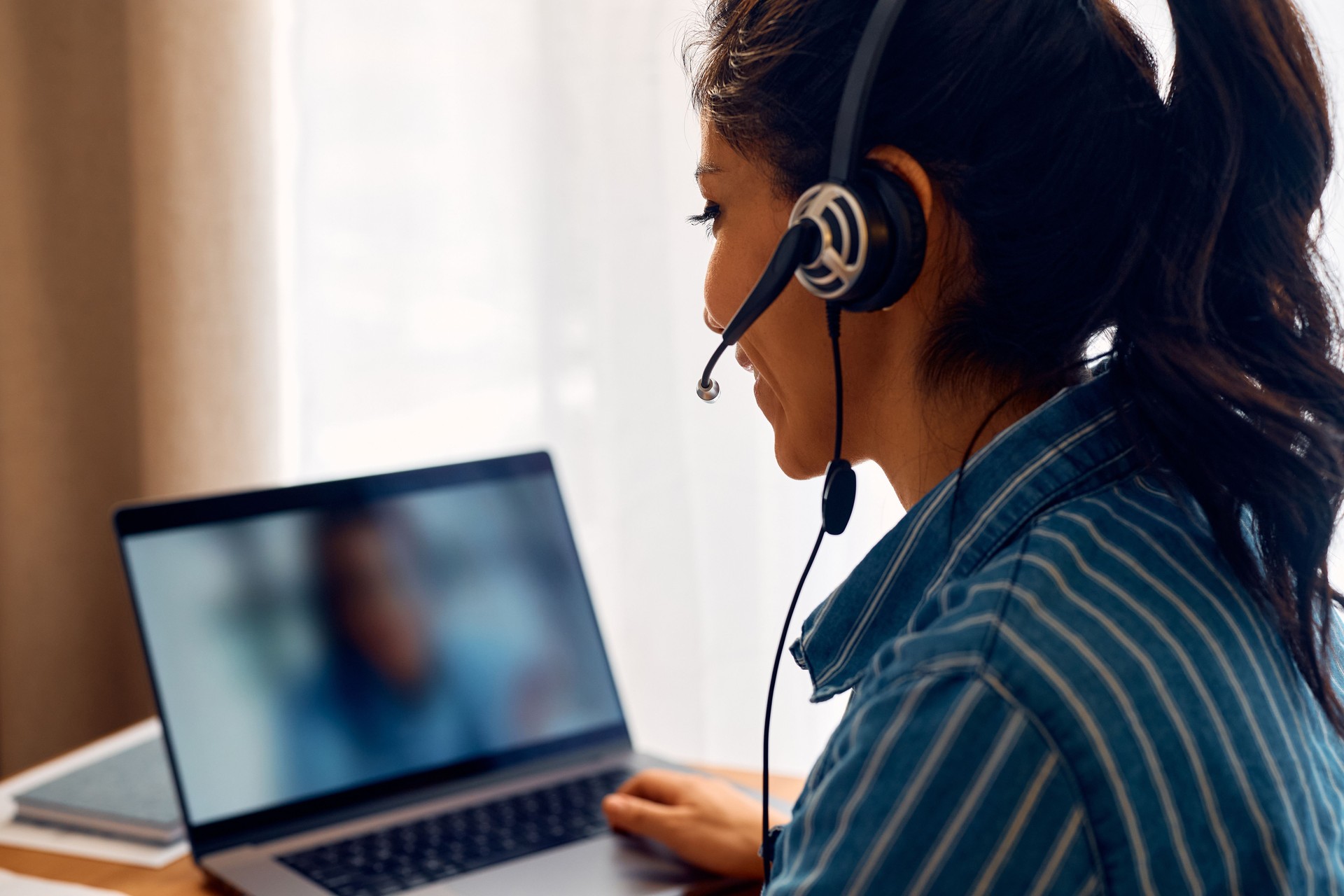 Female entrepreneur using laptop during video call at home office.